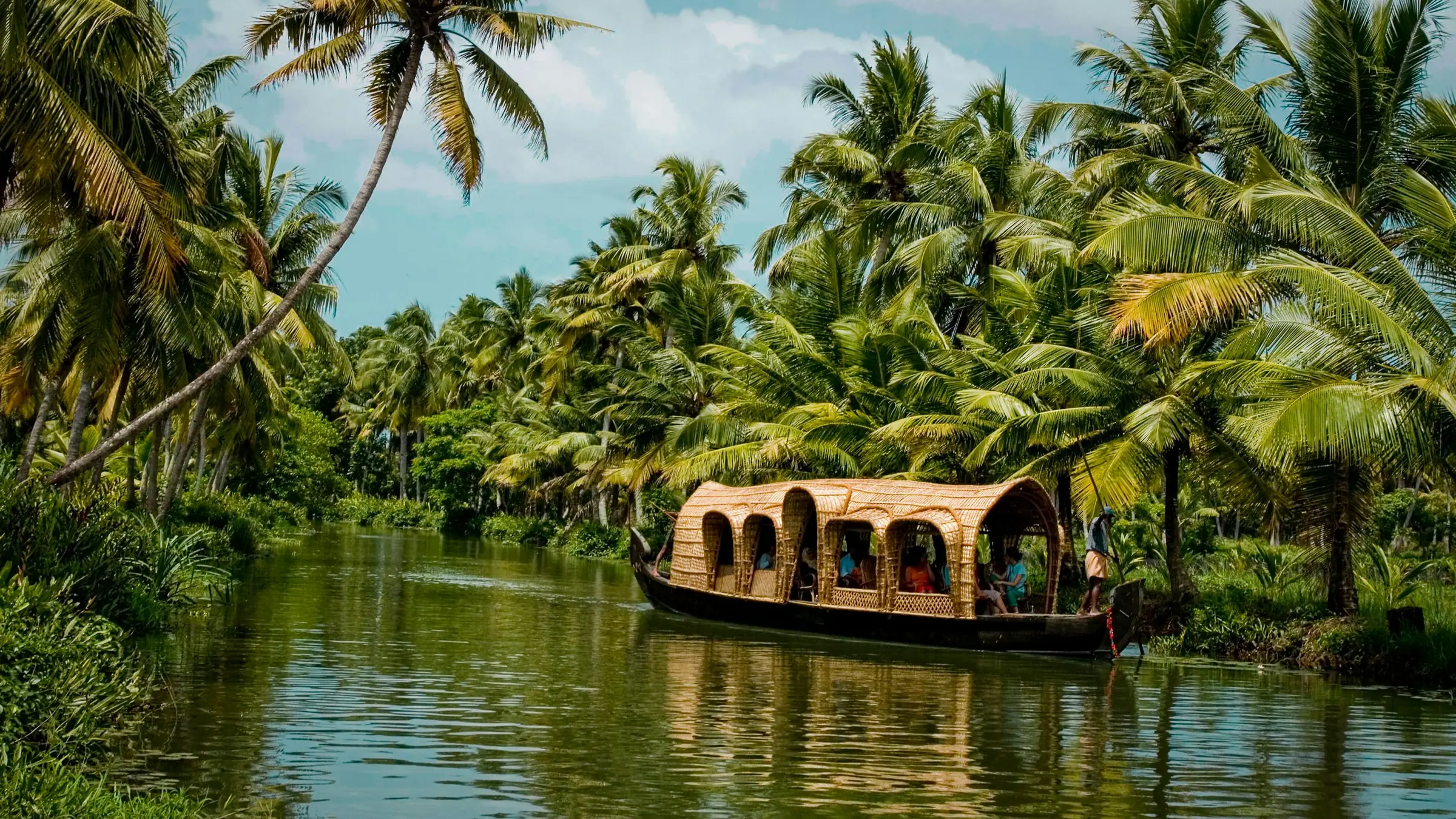 Ein Boot auf einem palmengesäumten Backwater in Kerala