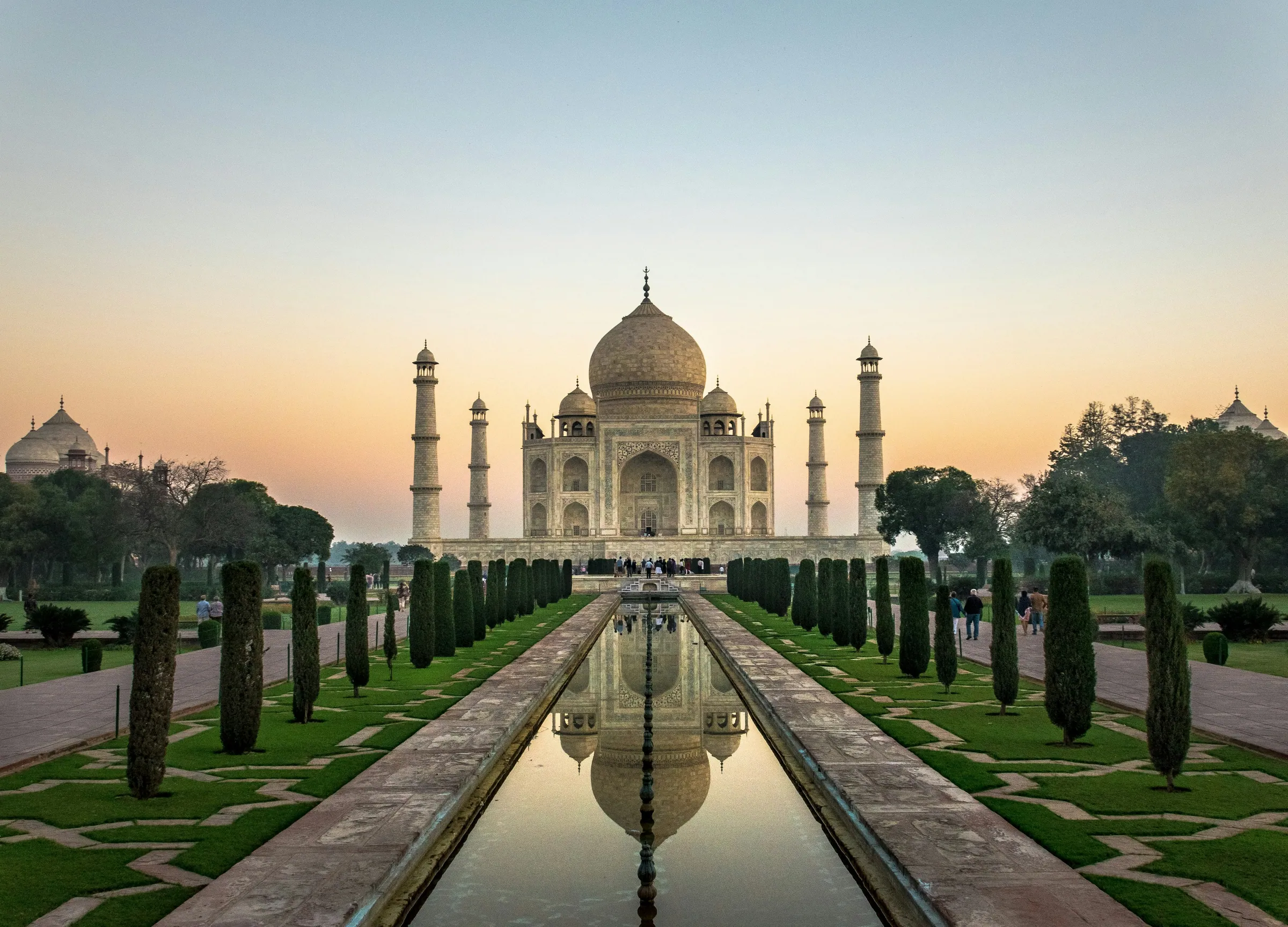Der Taj Mahal bei Sonnenaufgang, gespiegelt im langen Wasserbecken